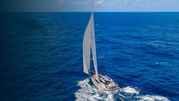 A yacht sailing with a clear horizon and blue skies