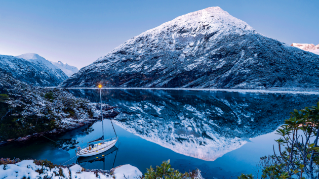 Still waters of Seno Garibaldi capture the mountain’s reflection, under a serene sky, at Caleta Scherzo.